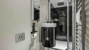 Ein modernes Badezimmer mit Waschbecken, Spiegel und einer Duschkabine aus Glas.