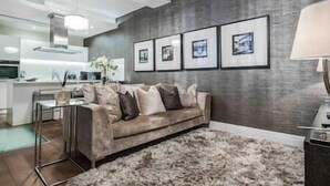 Ein modernes Wohnzimmer mit einem grauen Sofa, einem flauschigen Teppich und gerahmten Bildern an der Wand.