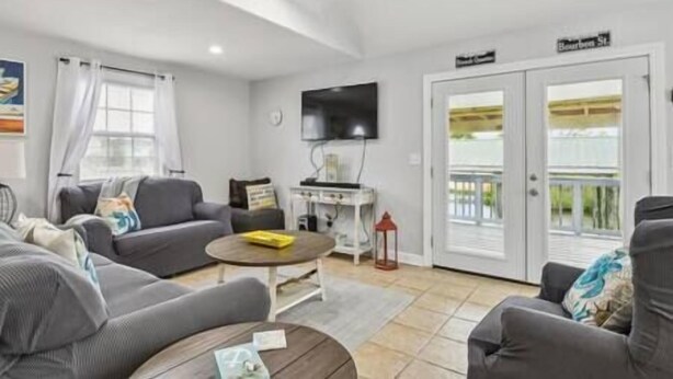 Ein Wohnzimmer mit Sofa, Couchtisch, Fernseher und Balkon.