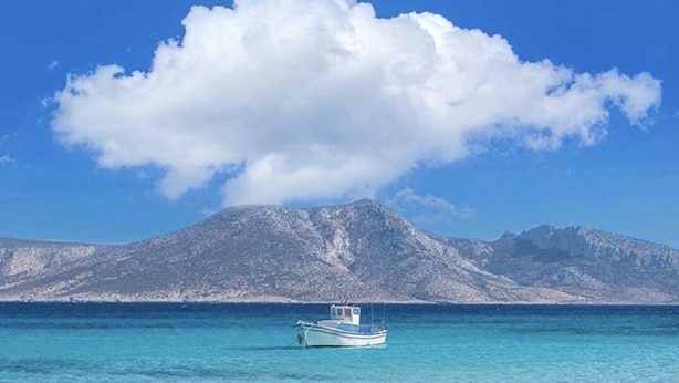 A boat on clear turquoise water with a mountain in the background.