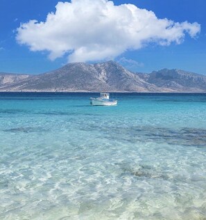 Ein Boot auf klarem türkisblauem Wasser, im Hintergrund ein Berg.