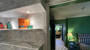 A bathroom with a marble sink, a mirror, and toiletries on a shelf.