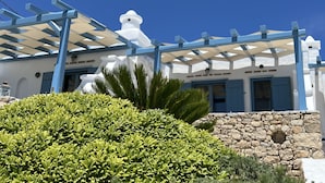A building facade with a pergola and stone wall.