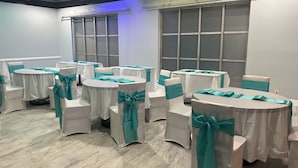 A room with round tables and chairs, each with teal sashes. - Apm Inn and Suite  (Jacksonville)