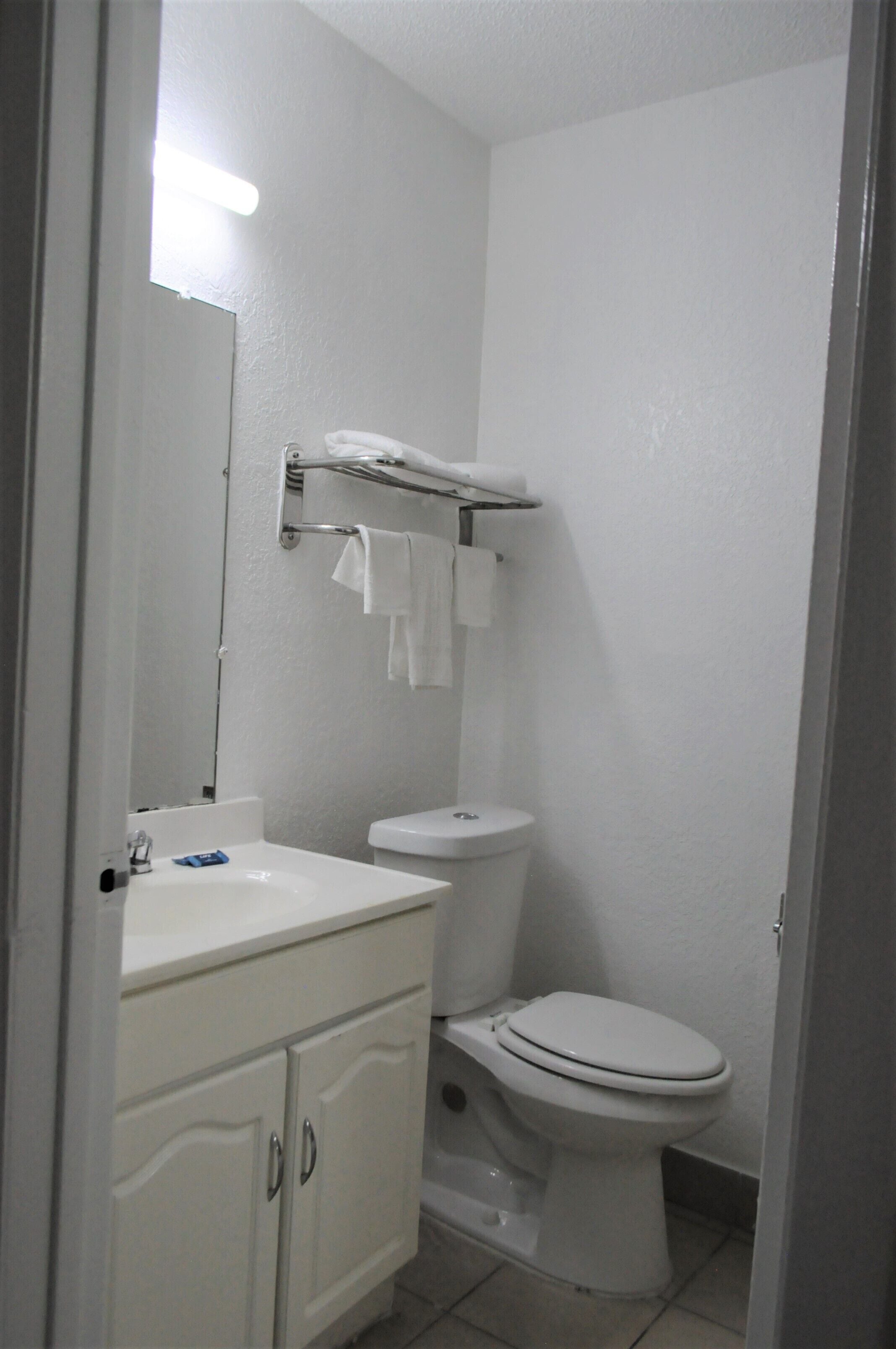 Un baño pequeño y limpio con lavamanos, tocador y retrete blancos.