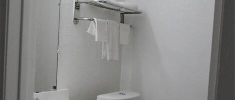 Un baño pequeño y limpio con lavamanos, tocador y retrete blancos.