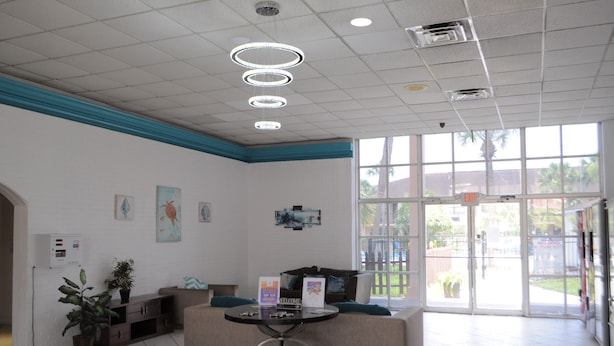 A reception area with a reception desk, seating, and a large window providing a view of the outdoors. - Apm Inn and Suite  (Jacksonville)