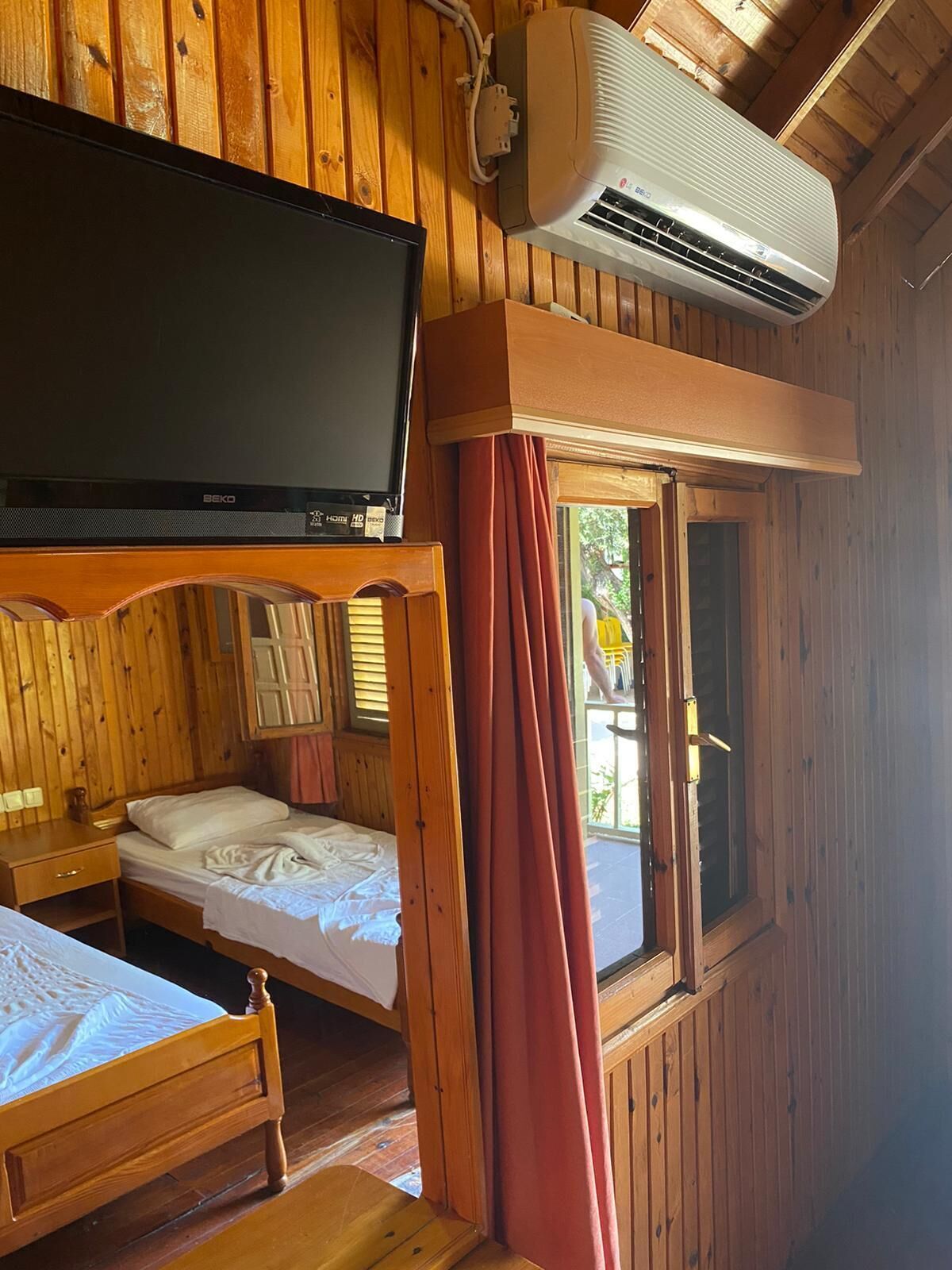 Una cabaña de madera con cama, televisor y aire acondicionado.