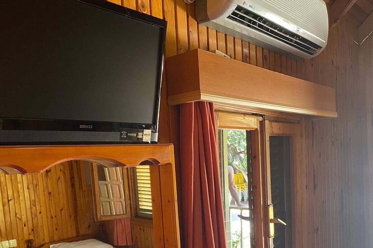 A wooden cabin with a bed, a TV, and an air conditioning unit.