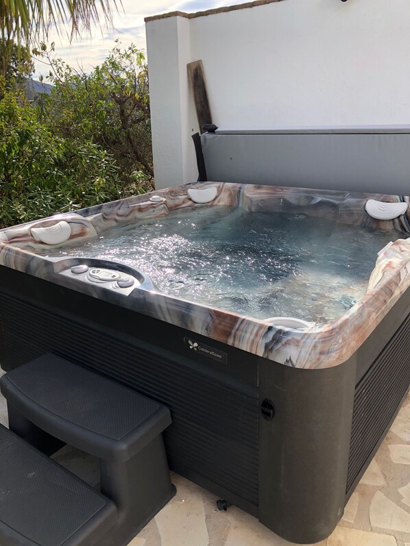 Un jacuzzi con revestimiento de mármol, un panel de control y un escalón para entrar.