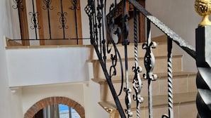 A staircase with ornate black metal railings and a wooden door at the top.