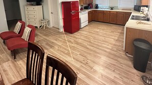 A spacious living area with a kitchen, wooden flooring, and a dining table with chairs.