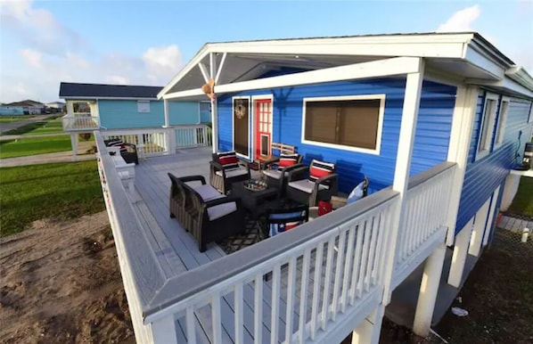 A blue mobile home with a covered porch, outdoor seating, and a red door.