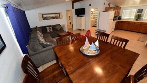 A dining area with a wooden table, chairs, and a cake with party hats.