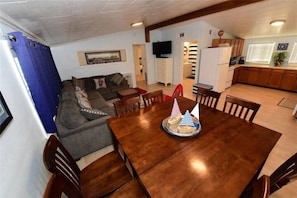 Enjoy meals and social gatherings in this spacious living area with a large dining table, comfortable sofa, and flat-screen TV.