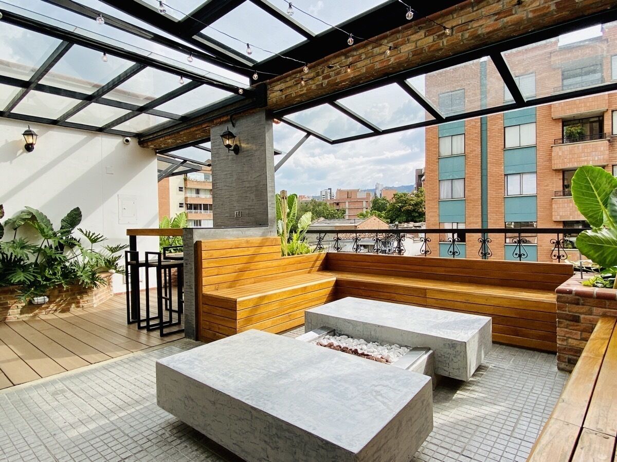 Eine Dachterrasse mit Holzmöbeln, einer Feuerstelle und einer Glaskuppel.