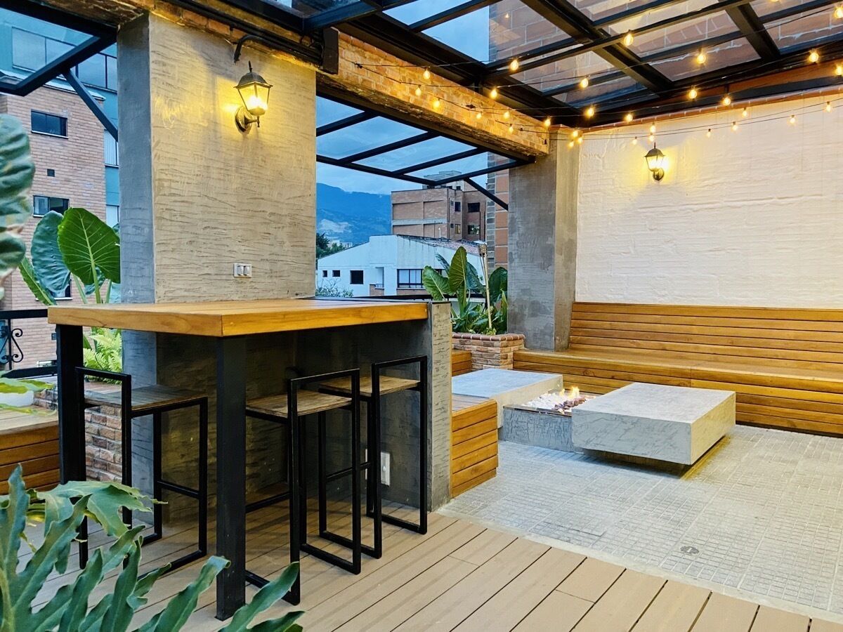 An outdoor seating area with a wooden bar, cushioned seating, and a stone planter.