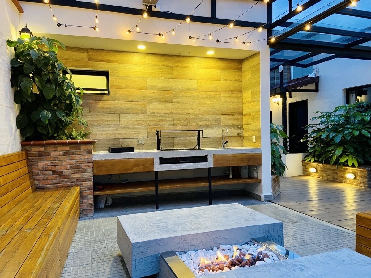 A modern outdoor kitchen area with a built-in counter, a fire pit, and string lights.
