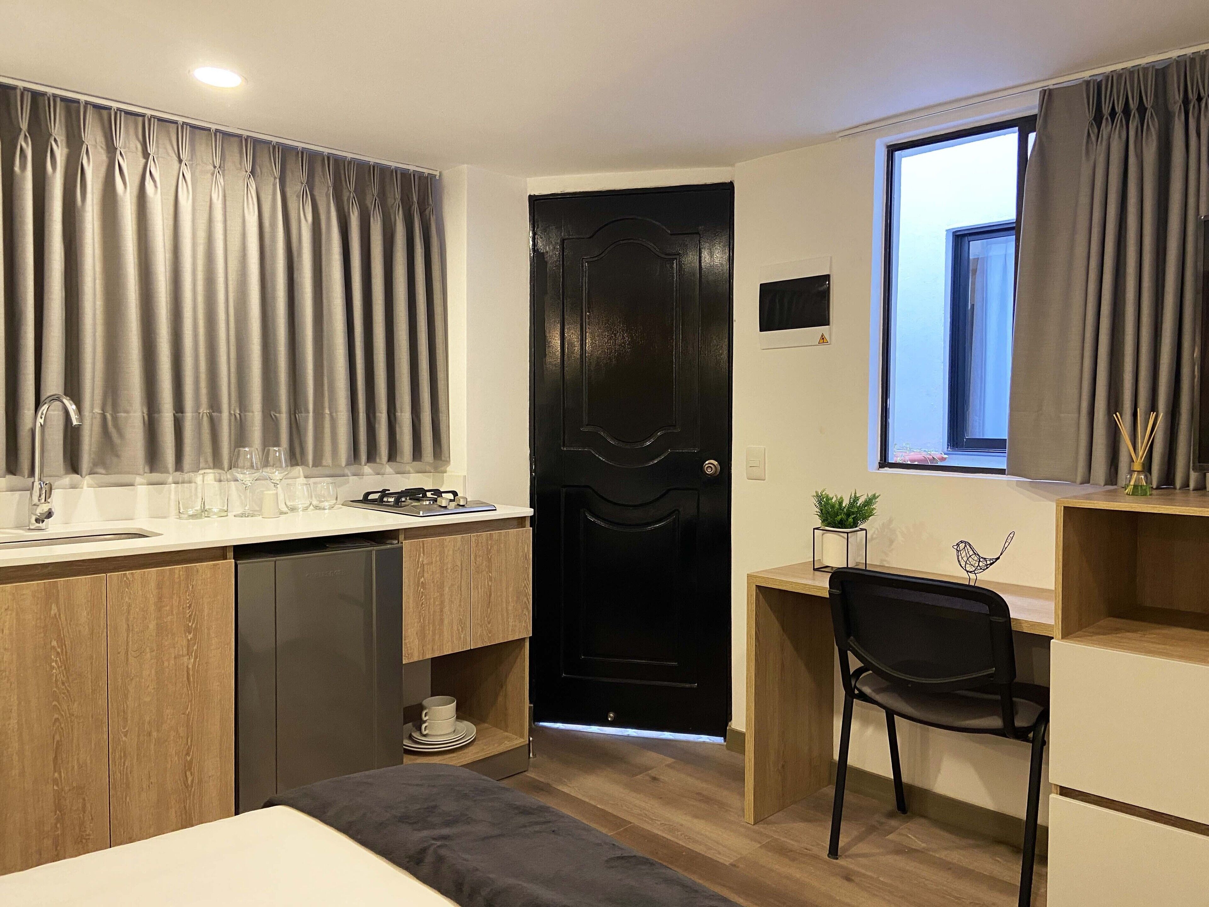 A compact bedroom with a bed, bedside table, and a desk with a chair.
