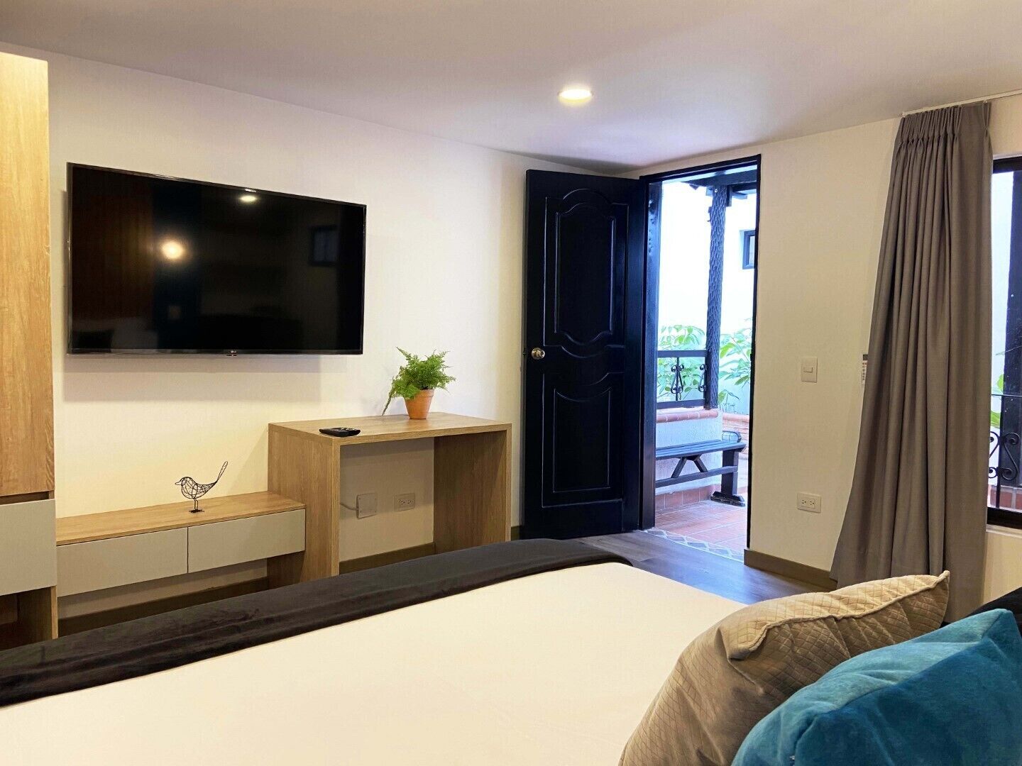 Habitación de hotel con cama, escritorio, televisión y puerta que da a un área exterior.