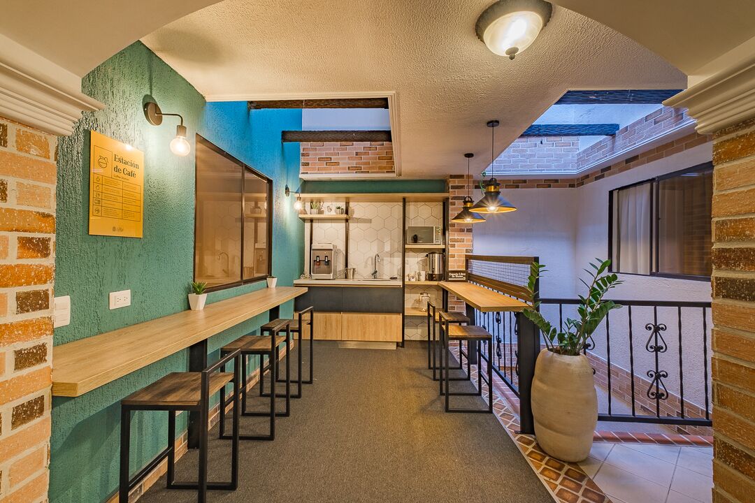 Een café met een bakstenen muur, houten tafels en een grote potplant.