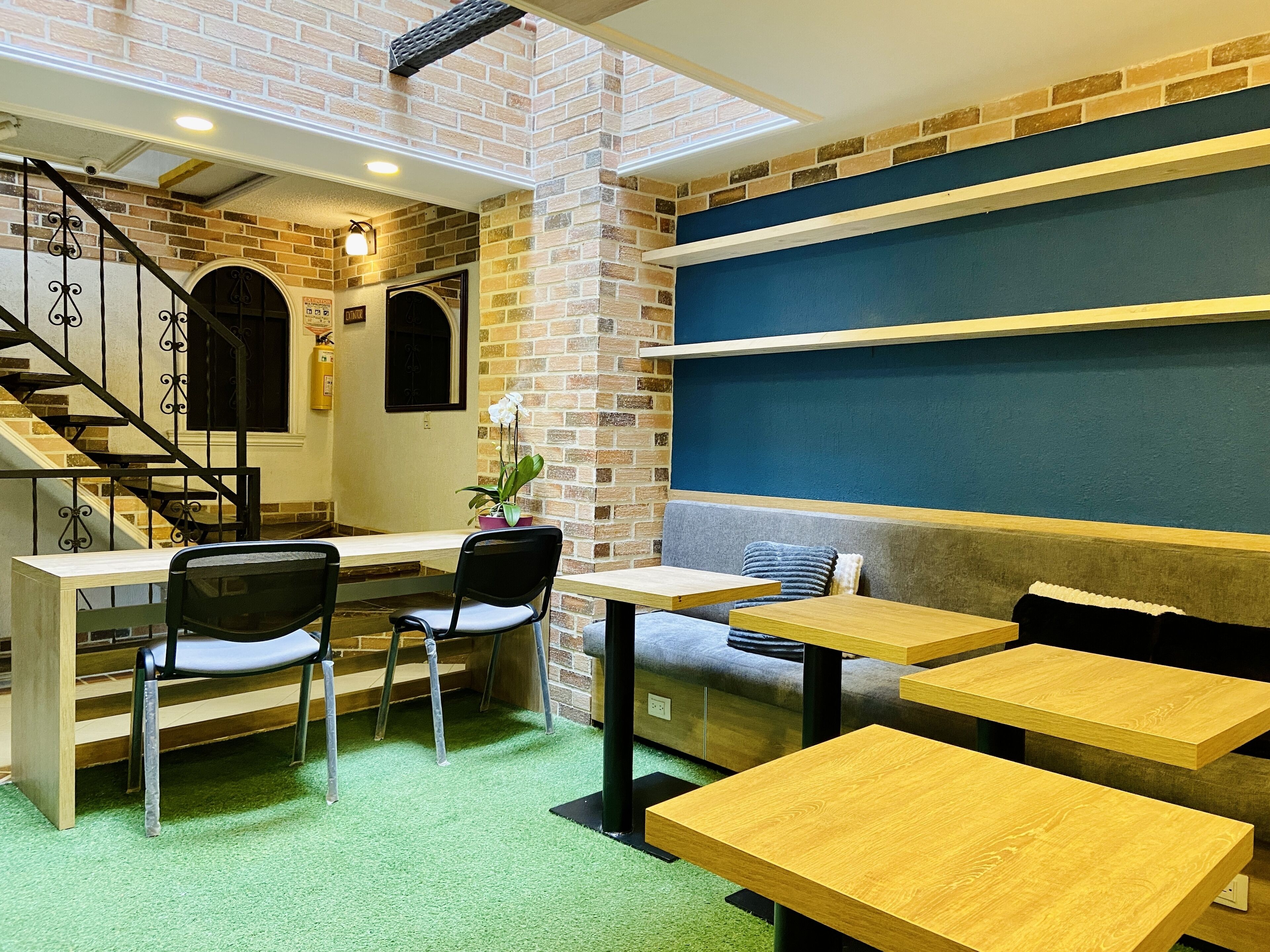 A cozy cafe with brick walls, a staircase, and wooden tables and chairs.