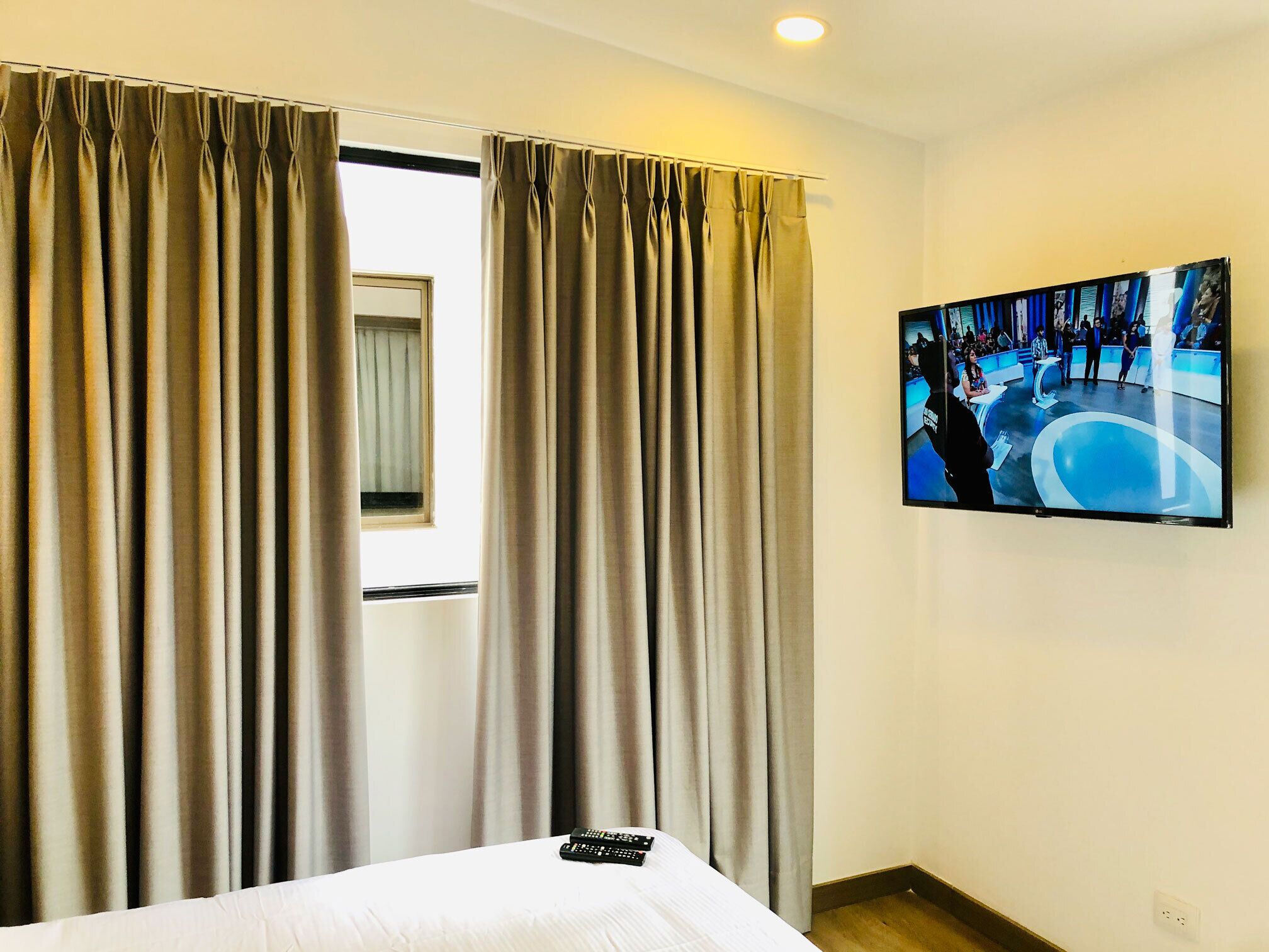 Ein Hotelzimmer mit Bett, Vorhängen, Fernseher und Fenster.