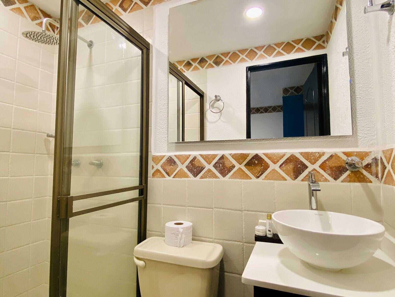 A bathroom with a glass shower enclosure, a toilet, a sink with a basin, and a mirror above the sink.