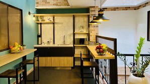 Cocina compacta con encimera de madera, un lavabo y una lámpara colgante.