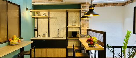 A compact kitchen with a wooden countertop, a sink, and a hanging light fixture.