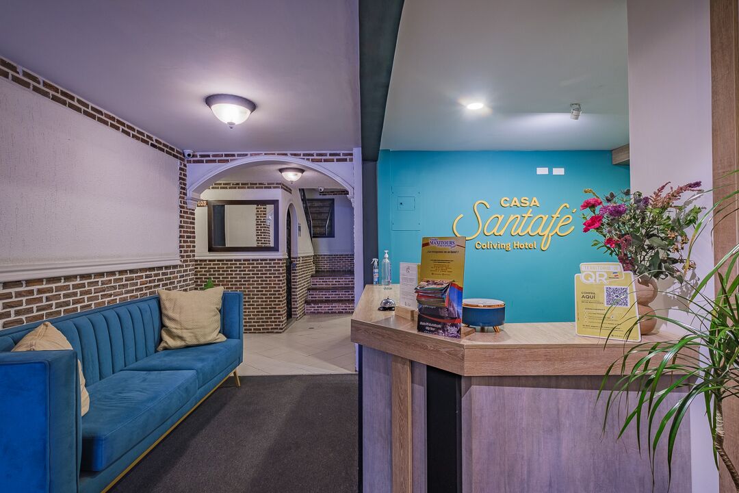 A reception area with a blue couch, a wooden reception desk, and a sign for Casa Santafé.