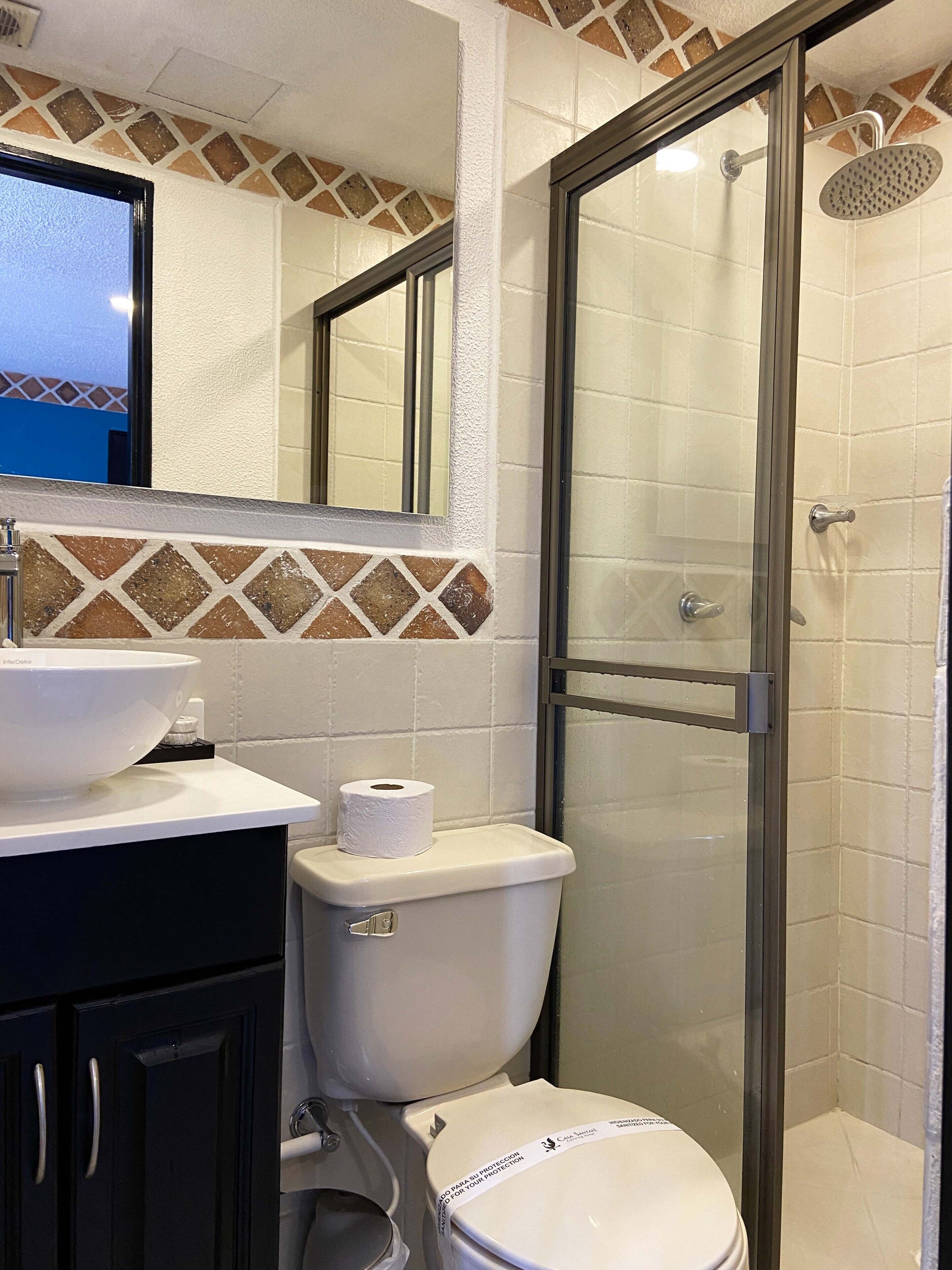A bathroom with a white sink, toilet, and shower.