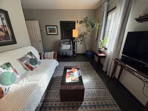 Sala de estar con sofá, sillón, mesa de centro, televisor y una planta en maceta.