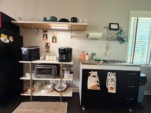 Una cocina compacta con horno integrado, cafetera y lavamanos.