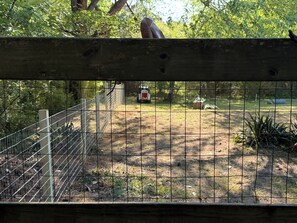 Un espace extérieur clos, doté d’une structure en bois, d’une clôture en métal et d’un véhicule visible à l’arrière-plan.