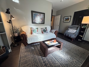 A living room with a sofa, a coffee table, a patterned rug, a floor lamp, and a chair.