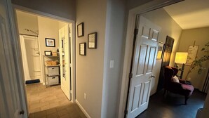A hallway with a door leading to a bathroom, a chair, and a lamp.