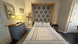 A bedroom with a bed, dresser, mirror, and a patterned headboard.