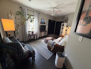 Un salon avec un canapé, une table basse, un téléviseur, un ventilateur de plafond et une plante en pot.