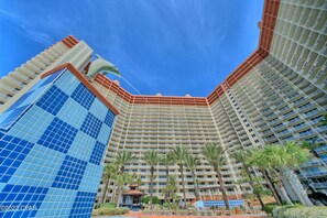 Un hotel modern amb nombrosos balcons, un atrium central i palmeres.