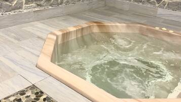 A hot tub with a stone wall backdrop and tiled flooring.