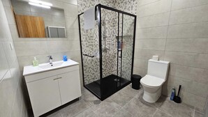 Une salle de bain équipée d’une douche, de toilettes et d’un lavabo avec des articles de toilette.