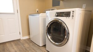 Une buanderie équipée de deux machines à laver à chargement frontal blanches et d’un sèche-linge.