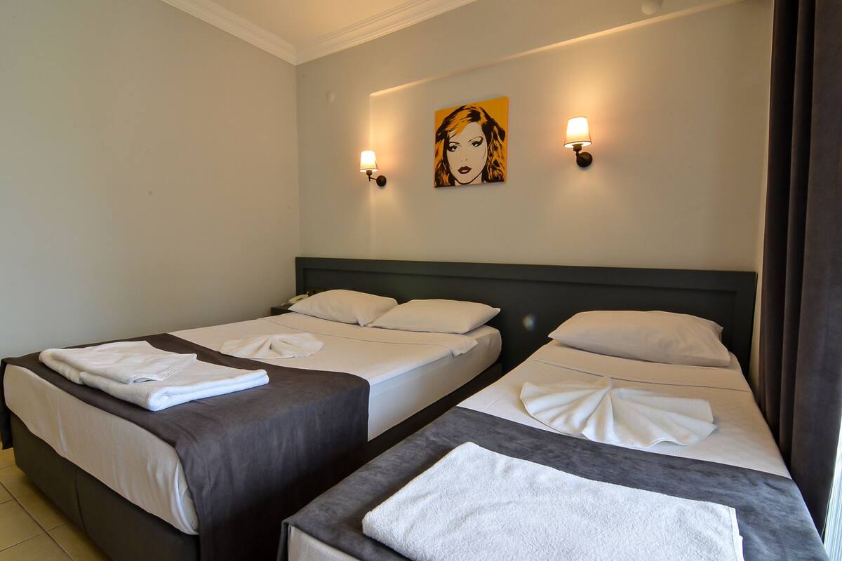 A hotel room with two beds, each with neatly made white linens and towels.
