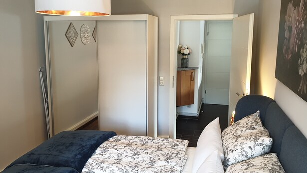 Ein Schlafzimmer mit einem Bett, einem Kleiderschrank und einer Tür zu einem anderen Raum.