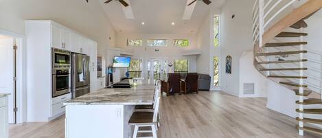 A spacious kitchen with a central island, white cabinetry, and a built-in oven.
