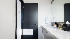 Une salle de bain moderne avec une porte noire, un plan de toilette blanc et un distributeur de serviettes.