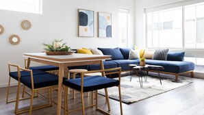 Un salon moderne avec un canapé bleu, une table à manger en bois et des chaises assorties.