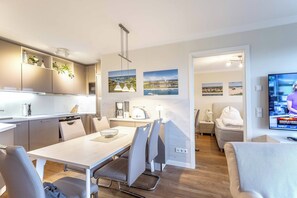 Una cucina moderna con zona pranzo, televisione e opere d'arte alle pareti.