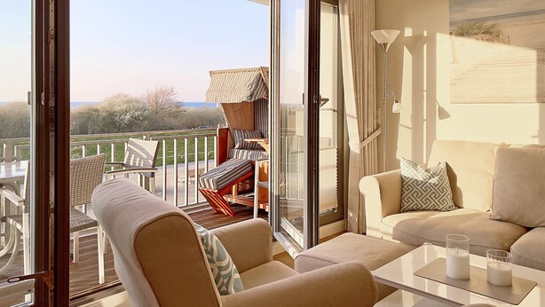 A balcony with a view of the beach, a sofa, a table with candles, and a chair. - Deichgraf 07, Direkter Meerblick aus Allen Drei Zimmern, 2 SZ, 2xbad, TG, Kamin (Börgerende-Rethwisch)